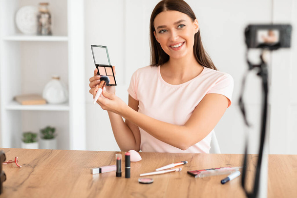 Blogger de beleza menina fazendo vídeo revisão de produtos cosméticos em casa
 - Foto, Imagem
