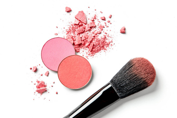 Кисть макияжа и измельченные розовые тени для глаз изолированы на белом
 - Фото, изображение