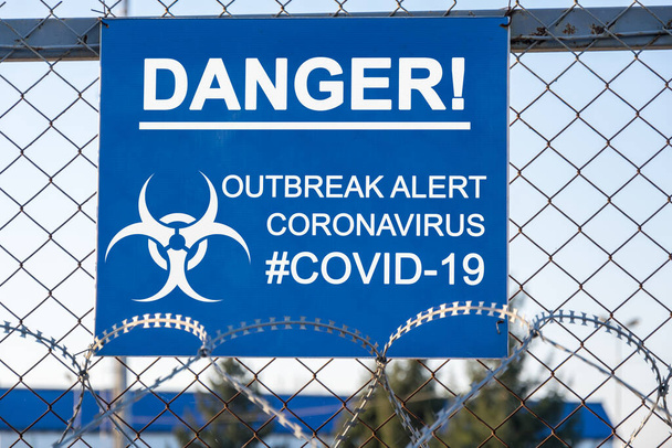 Yazı "Tehlike! Tehlike! Salgın alarmı: Coronavirus # covid-19 "ve dikenli telle çevrilmiş demir tel üzerinde mavi bir plaka üzerindeki biyolojik tehlike uyarısı. Kapalı alan. Karantina ve tecrit kavramı - Fotoğraf, Görsel