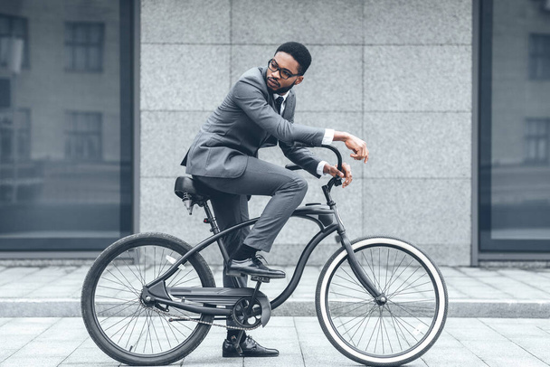 Przystojny afro biznesmen jazda na rowerze do pracy - Zdjęcie, obraz