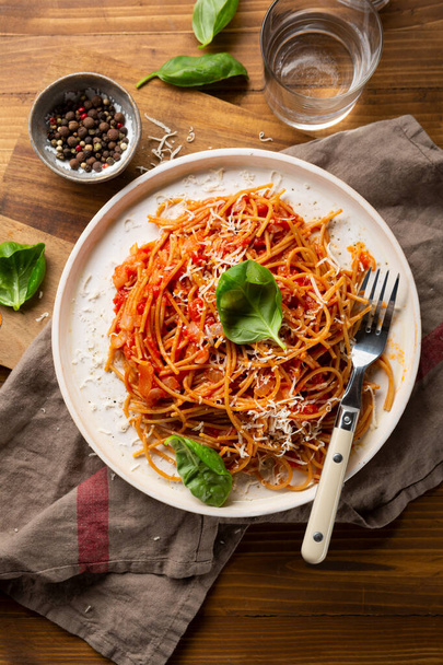 Whole wheat spaghetti  with tomato sauce on wooden table - Photo, image