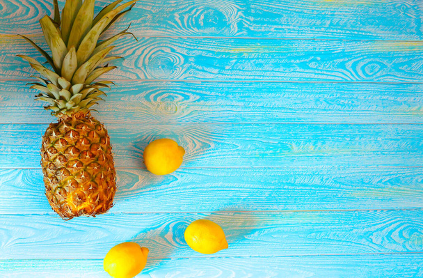 Ананас и три желтых лимона на синем деревянном фоне. Летняя концепция. Фрукты и витамины Все для здоровой диеты. Диета и фитнес
 - Фото, изображение
