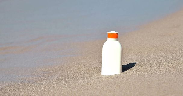 Botella con crema de protección solar sobre textura de arena. - Foto, Imagen