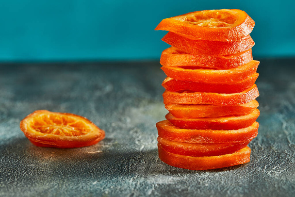Slices of dried oranges or tangerines on a blue background. Vegetarianism and healthy eating. Copy space - Photo, Image