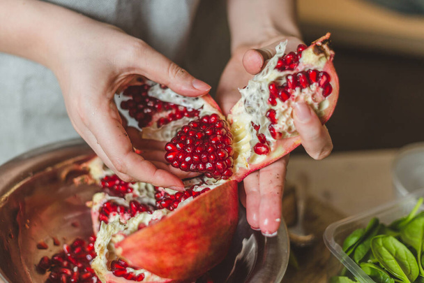 Young hands of the girl cut and cleaned fresh juicy pomegranate - a healthy diet - Φωτογραφία, εικόνα