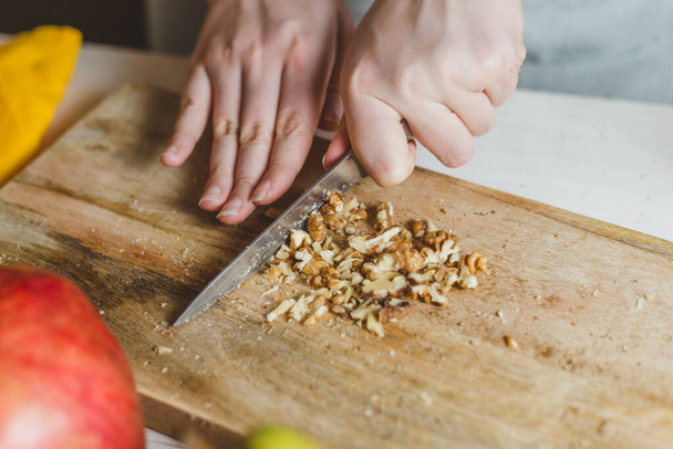 Walnut slicing on a wooden board - homemade recipe - housewife's hands - selective focus - Fotó, kép