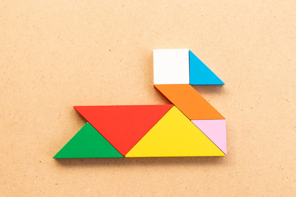 Kleur tangram puzzel in zwaan of eend vorm op hout bacground - Foto, afbeelding