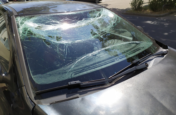 A törött szélvédő üvege egy súlyos autóbaleset után tönkretette a szélvédőt, és olyan sérülést okozott, ami összetörte és betörte az üveget, hogy megmutassa, szükség van gépjármű-felelősségbiztosításra. - Fotó, kép