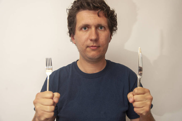 Jeune homme avec fourchette et couteau. Concept de prêt à manger, faim, délicieux
. - Photo, image