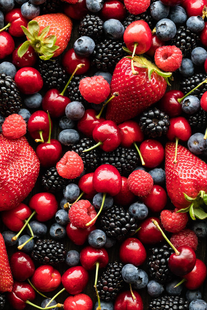 A top down view of a variety of berries and cherries in a pile. - Photo, Image