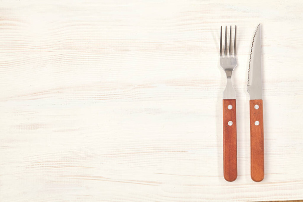 Tenedor y cuchillo sobre mesa de madera con espacio para copiar. Vista superior
. - Foto, imagen