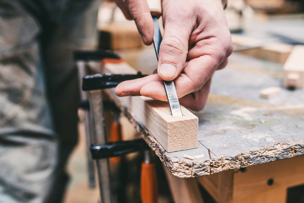 Manual processing of wood in the carpentry workshop - the master works with a chisel - 写真・画像