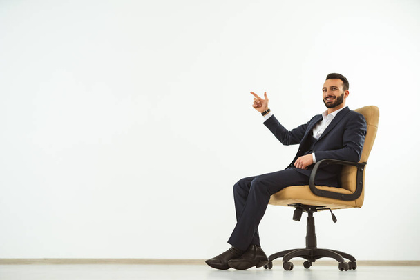 Ο χαρούμενος επιχειρηματίας κάθεται σε μια καρέκλα γραφείου και gesturing - Φωτογραφία, εικόνα