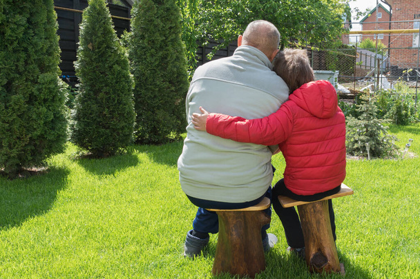  taustakuva isoisä ja pojanpoika istua puinen tuolit vihreässä puutarhassa ja halaus, parhaat ystävät, lämmin viestintä sukupolvien välillä. Huolehdin vanhemmasta sukupolvesta. Isän päivän käsite
 - Valokuva, kuva