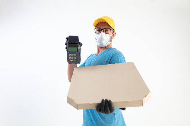 Delivery guy with protective mask holding pizza box and POS for contactless payment. - Fotó, kép