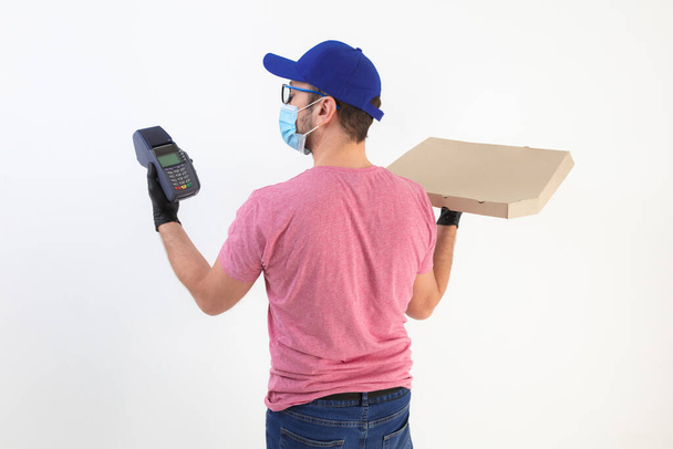 Livraison gars avec masque de protection tenant boîte à pizza et POS pour le paiement sans contact
. - Photo, image
