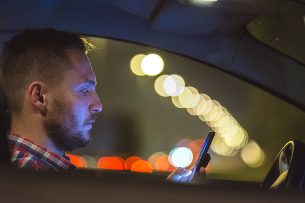El hombre telefonea dentro del coche en la carretera. noche noche tiempo
 - Foto, Imagen