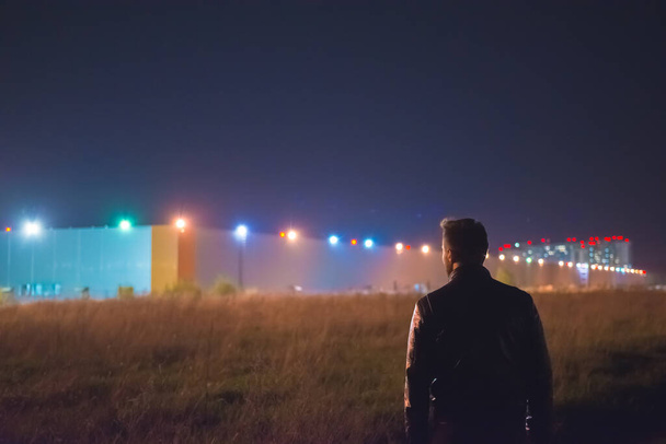 Мужчина стоит возле здания. вечернее время
 - Фото, изображение