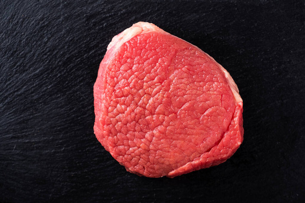 Raw meat steak on a black stone. Top view - Photo, Image