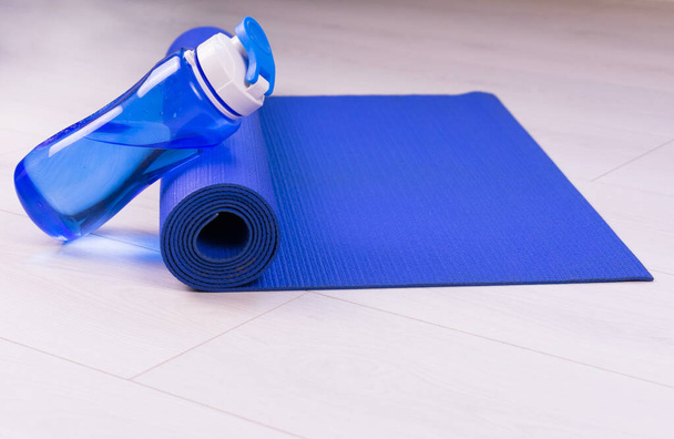 Sportkonzept. Blaue Wasserflasche und Yogamatte. Kopierraum. - Foto, Bild
