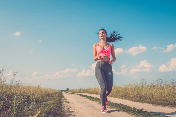 La mujer del deporte corriendo en el camino de campo
 - Foto, Imagen