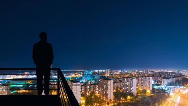 L'homme debout sur le dessus du bâtiment sur le fond du paysage urbain nocturne
 - Photo, image