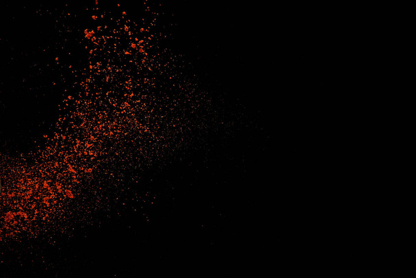 Red paprika spices powder explosion, flying chili pepper isolated on black background. Splash of spice background.  - Photo, image