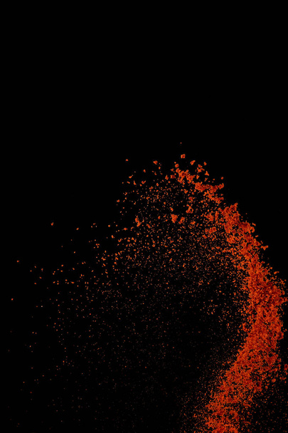 Red paprika spices powder explosion, flying chili pepper isolated on black background. Splash of spice background.  - Foto, Imagen