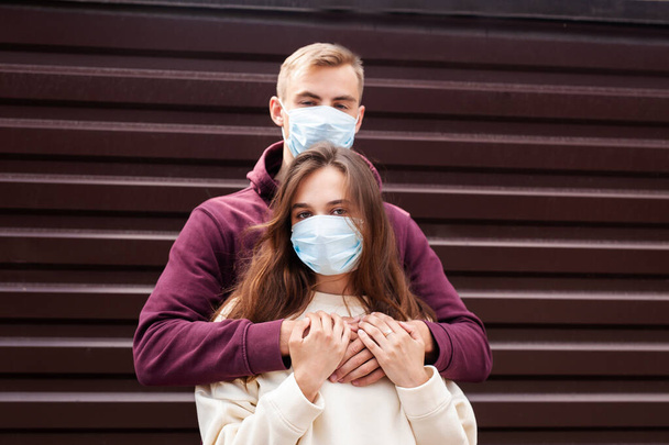 Young couple hugging wearing a face protection mask in the city since new coronavirus Covid 19 - Fotografie, Obrázek