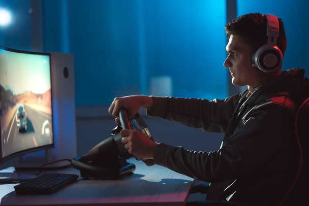 ヘッドフォンで男のゲーマーは、彼のパーソナルコンピュータ上でビデオゲームをプレイ  - 写真・画像