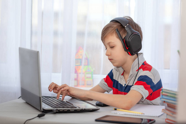 Portrait kid in headphones typing on computer, studying in home. Education knowlege, technology internet, homesschooling concept. - Foto, imagen