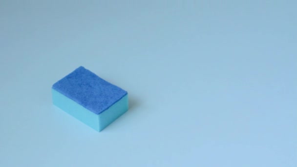 La esponja está en una superficie azul y una mano masculina en un guante de goma naranja está poniendo un cepillo y una botella de plástico de vidrio y azulejo limpiador
. - Metraje, vídeo