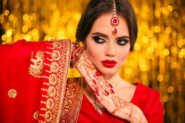 Retrato de hermosa chica india en sari nupcial rojo sobre dorado
 - Foto, imagen