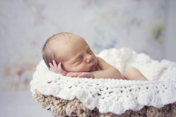 Neugeborenes Baby schläft in Korb auf weißer gehäkelter Decke Schwarz-Weiß-Bild - Foto, Bild