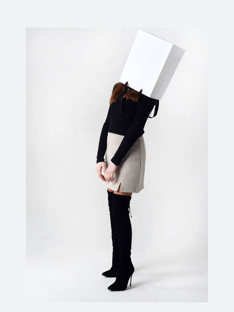Portrait of teen girl with paper bag over head. Teenager cover head with bag with crossed arms. - Фото, изображение