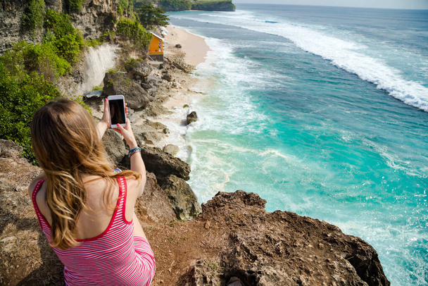 Woman tourist takign photos with her smartphone at a vacation on tropical island. - Photo, Image