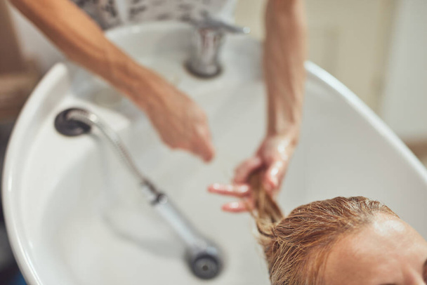 Hair dresser washing hair to a customer in the salon.  - Fotó, kép
