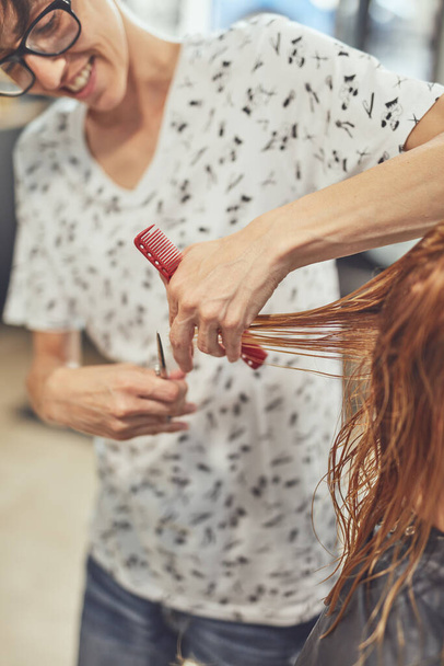 Hair dresser cutting hair in a salon. - Foto, imagen