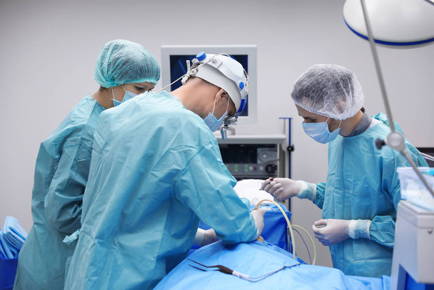 Team of professional doctors performing operation in surgery room - Valokuva, kuva
