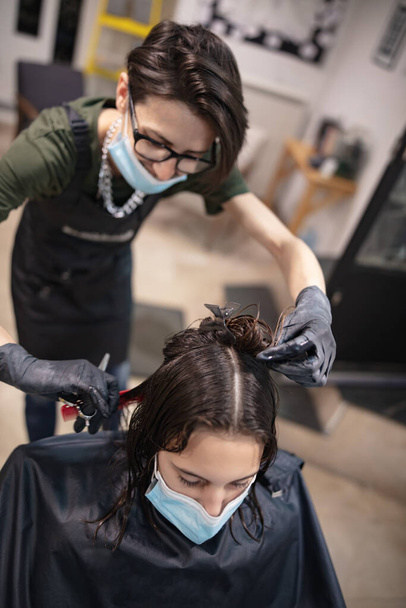 Fryzjer i dziewczyna klient dziecka w salonie z maskami medycznymi podczas pandemii wirusa. Praca z maską bezpieczeństwa. - Zdjęcie, obraz