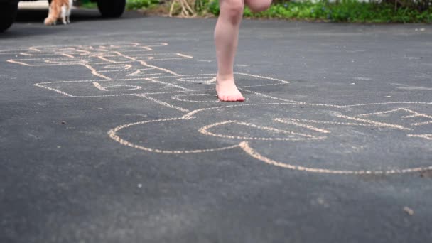 little girl playing hopscotch game barefoot in driveway - Footage, Video
