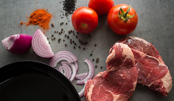 Steaks de bœuf cru, légumes frais, épices et herbes sur une table. Ingrédients frais vue du dessus photo
.  - Photo, image