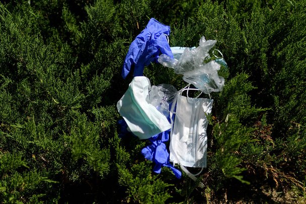 Eine Gruppe Masken und Handschuhe, die auf einem Busch liegen. Der Abfall aus dem covid19. Selektiver Fokus. - Foto, Bild