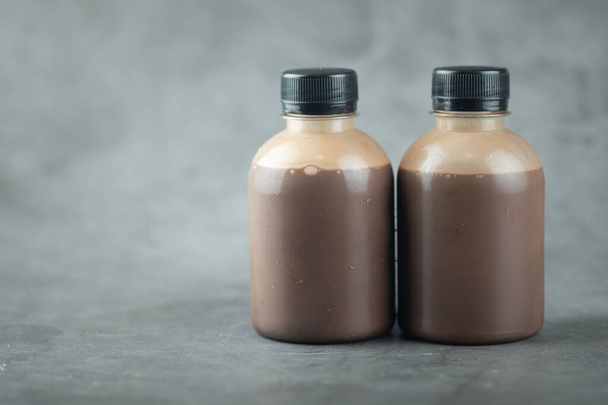 Две пластиковые бутылки вкусного какао-молока на черном фоне
 - Фото, изображение