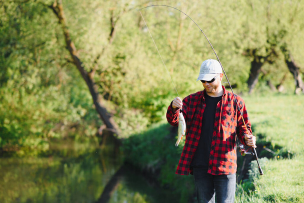 Man relaxing and fishing by lakeside. Weekends made for fishing. Fisher masculine hobby. Master baiter. Keep calm and fish on. Fishman crocheted spin into the river waiting big fish. Guy fly fishing - Fotografie, Obrázek