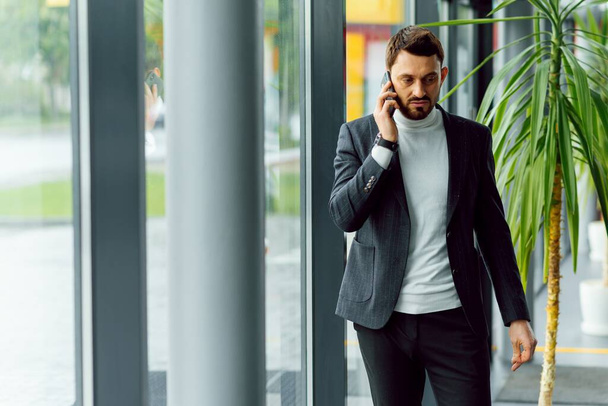 Young businessman standing in office hall and talking on phone - Foto, immagini
