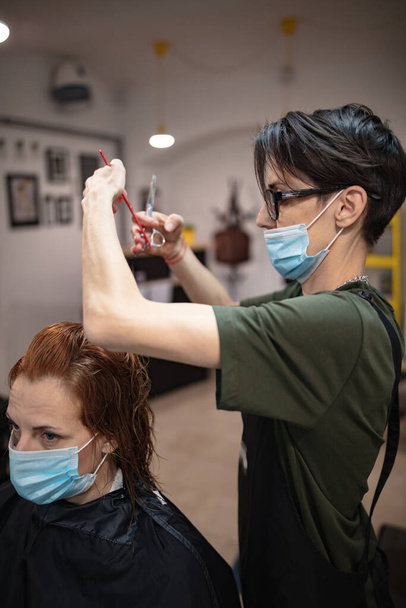流行時に医療用マスク付きサロンで美容師や顧客。安全マスクの使用. - 写真・画像