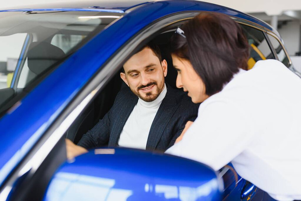 Salesperson selling cars at car dealership - Photo, Image