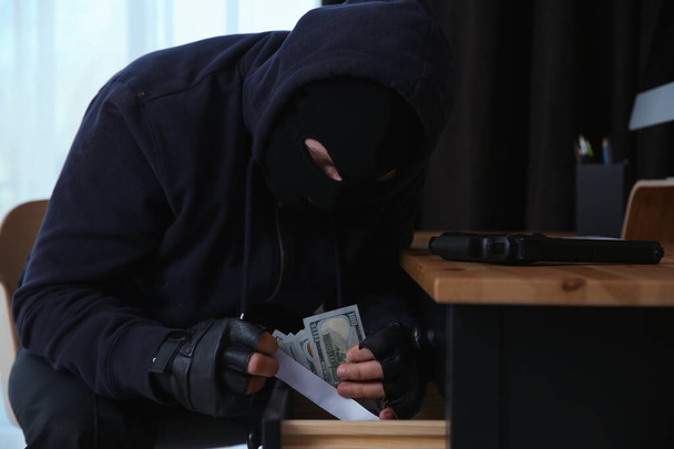 Dangerous masked criminal stealing money from house - Fotoğraf, Görsel