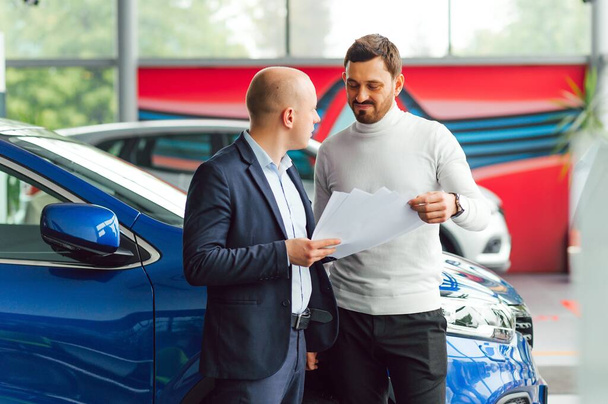 Salesperson selling cars at car dealership - Fotoğraf, Görsel